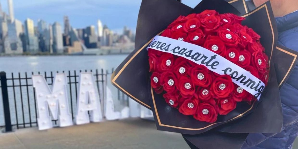 Red rose bouquet with a marriage proposal ribbon.