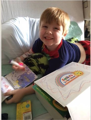 A patient smiling after receiving a Smile Box full of toys while he undergoes treatment 