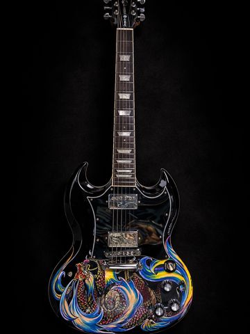 Black electric guitar with vibrant, colorful dragon artwork on the body.
