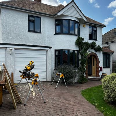 A white two-story house with construction tools on the driveway.