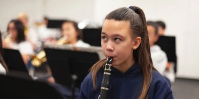 young girl playing clarinet in band room
