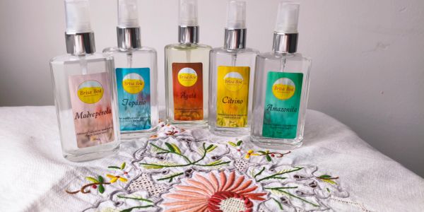 Frascos de perfumes coloridos sobre tecido bordado.