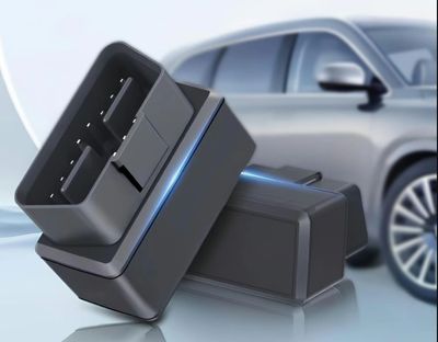 Close-up of a black car diagnostic tool with a blurred car in the background.