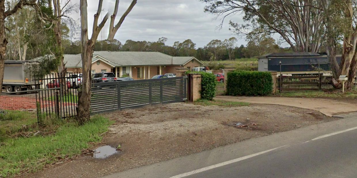 Rural property with a gated entrance and several parked vehicles.
