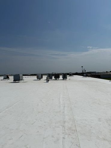 Flat white rooftop with multiple ventilation units under a bright blue sky.