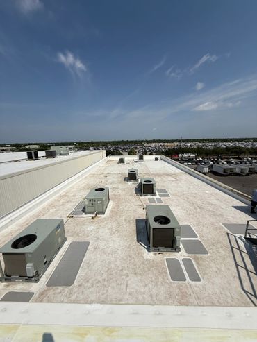 Flat rooftop with multiple HVAC units under a clear sky.