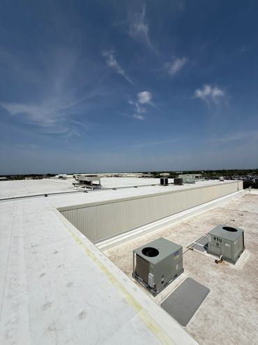 Wide rooftop view with HVAC units under a blue sky.