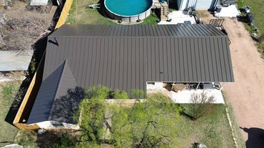 Aerial view of a house with a metal roof and a backyard pool.