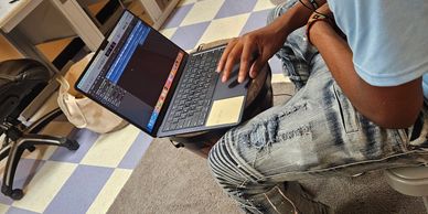 Person using a laptop, sitting on a chair in a room with checkered flooring.