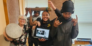 A diverse group joyfully posing with musical instruments and a laptop.