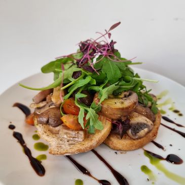 Mushrooms and tomatoes on sourdough toast, with rocket on top and a decorated plate