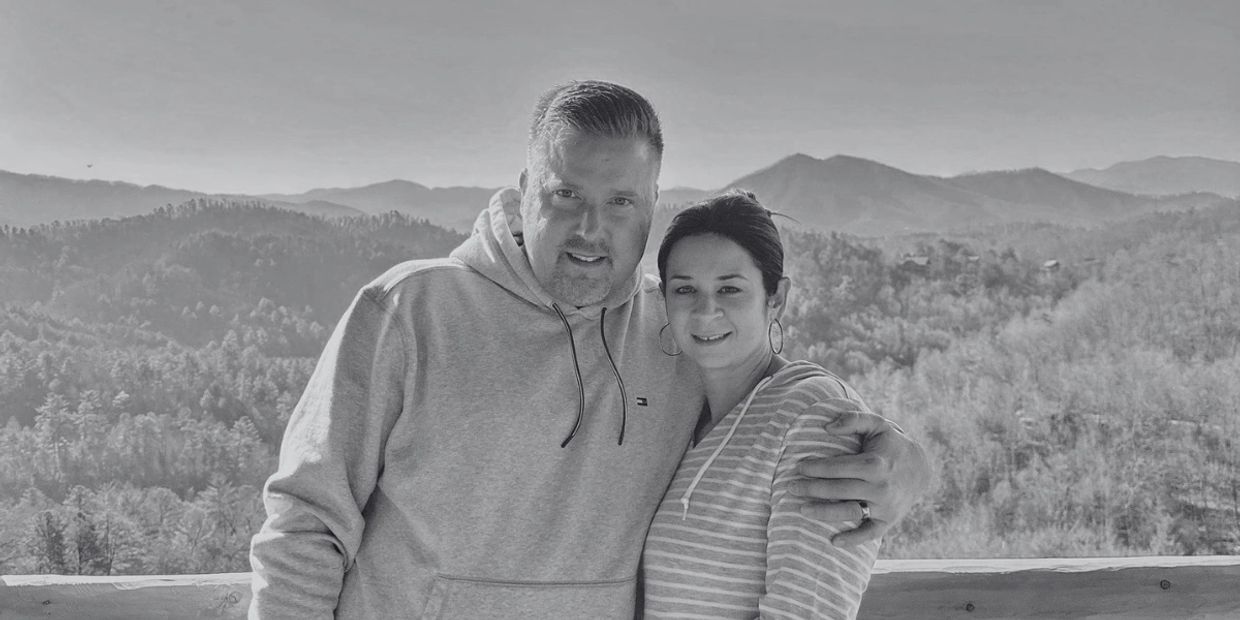 Couple posing in front of a scenic mountain landscape.