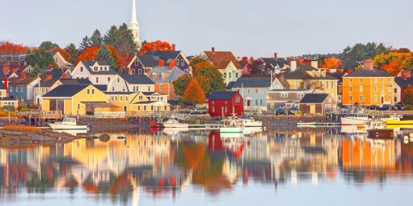 Quaint coastal town with colorful houses reflecting on calm water.