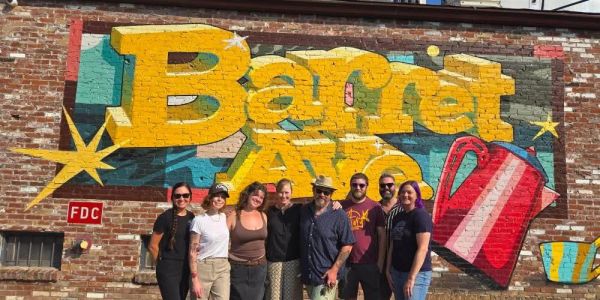 Group photo in front of colorful Barret Ave mural.