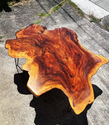Unique live edge wooden table with rich grain patterns on metal legs.