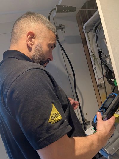 Technician inspecting electrical panel with a handheld device.