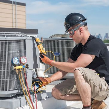 A technician inspects an air conditioning unit on a rooftop.