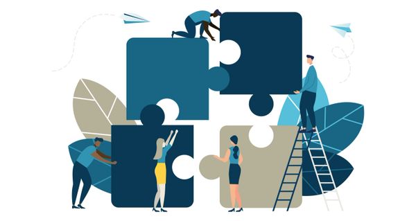People collaborating to assemble large puzzle pieces symbolizing teamwork.
