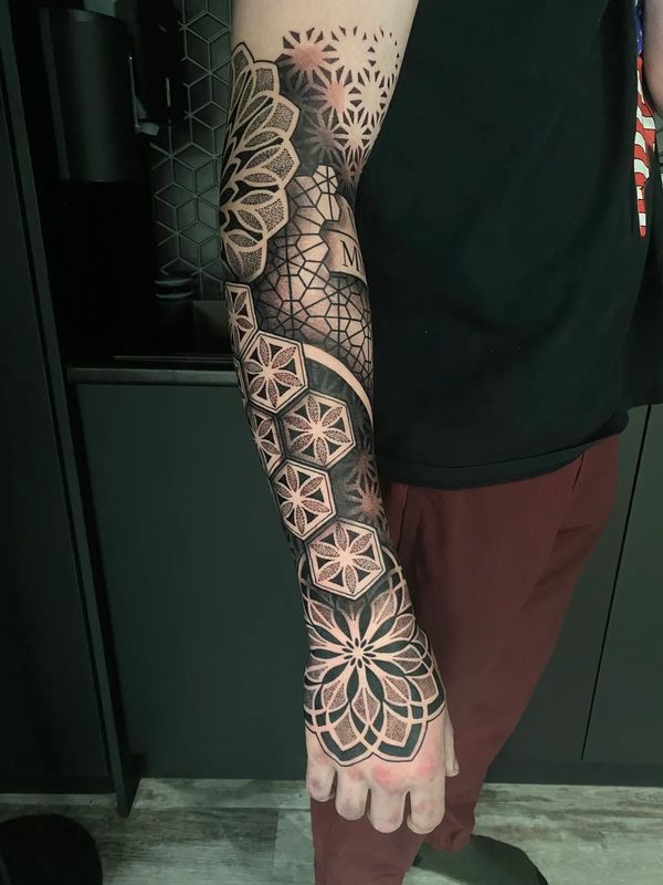 a detailed flowing, half sleeve tattoo with hexagons, flower of life, a Mandala on the hand, and lay
