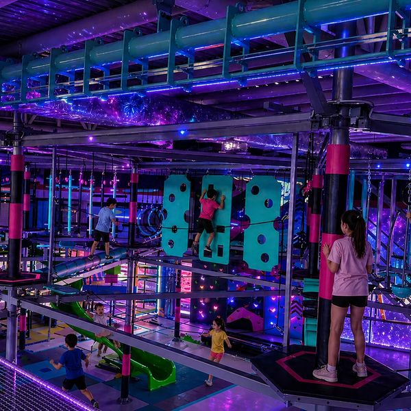 Children engaging in a neon-lit indoor obstacle course playground.
