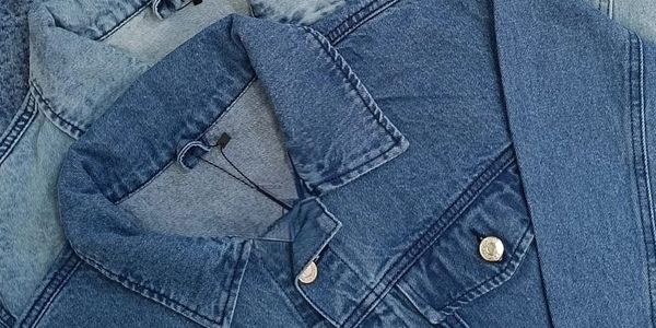 Close-up of folded denim jackets with visible collars and buttons.