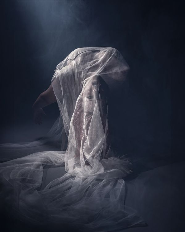 A woman appears to be levitating under a sheer cloth