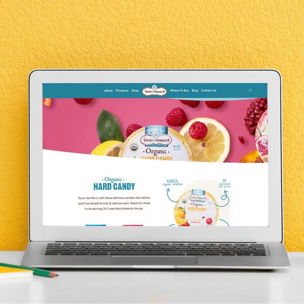 Laptop displaying Torie & Howard organic hard candy website against a yellow wall.