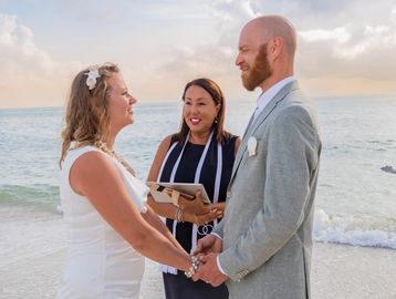 Couple exchanging vows on a beach with an officiant.