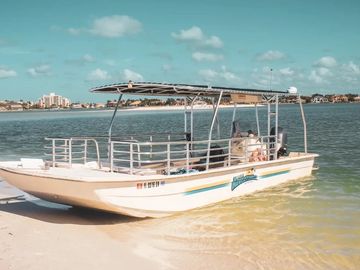 A small boat docked near the sandy shore on a sunny day.