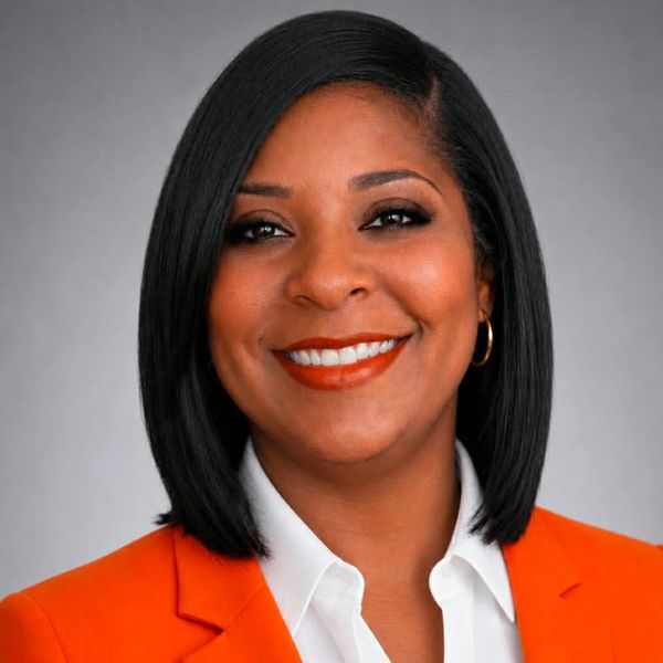 Confident woman smiling with orange blazer and white shirt.