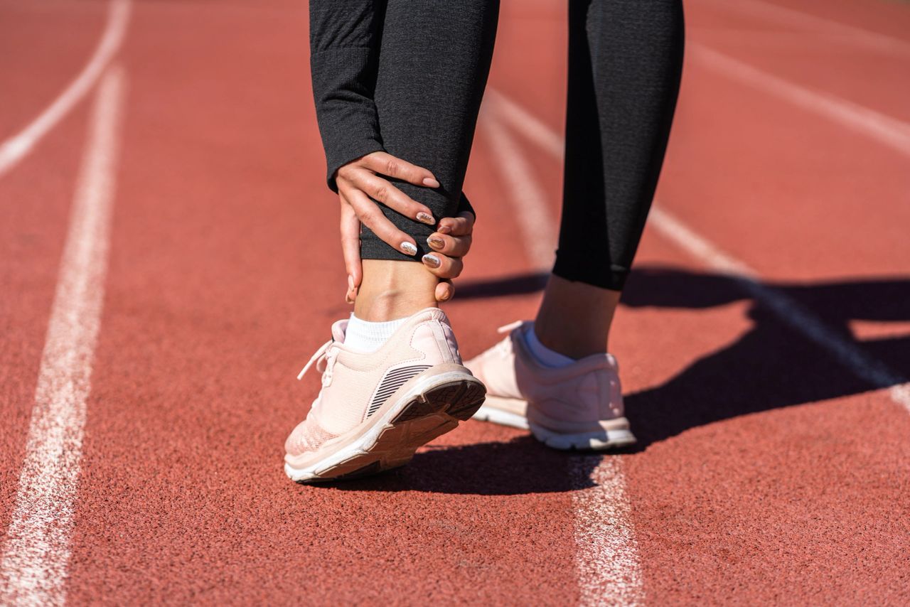 woman jogging grabbing her ankle woman jogging grabbing her ankle
