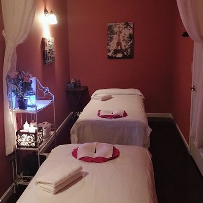 Relaxing massage room with two tables and soft lighting.
