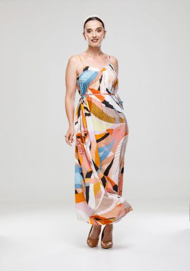 Woman in colorful abstract maxi dress and beige heels.