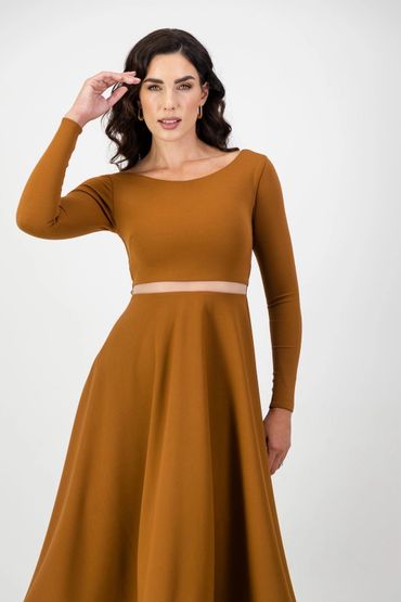 Woman in a mustard-colored long sleeve dress with a cutout waist.