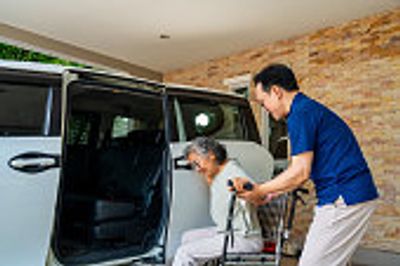 A man assisting a woman into a car door.