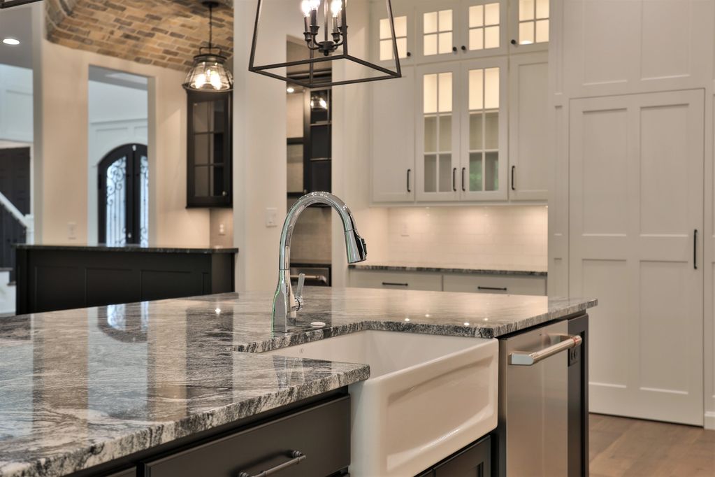 custom kitchen cabinetry with custom tile, trim, countertops with a unique pantry door