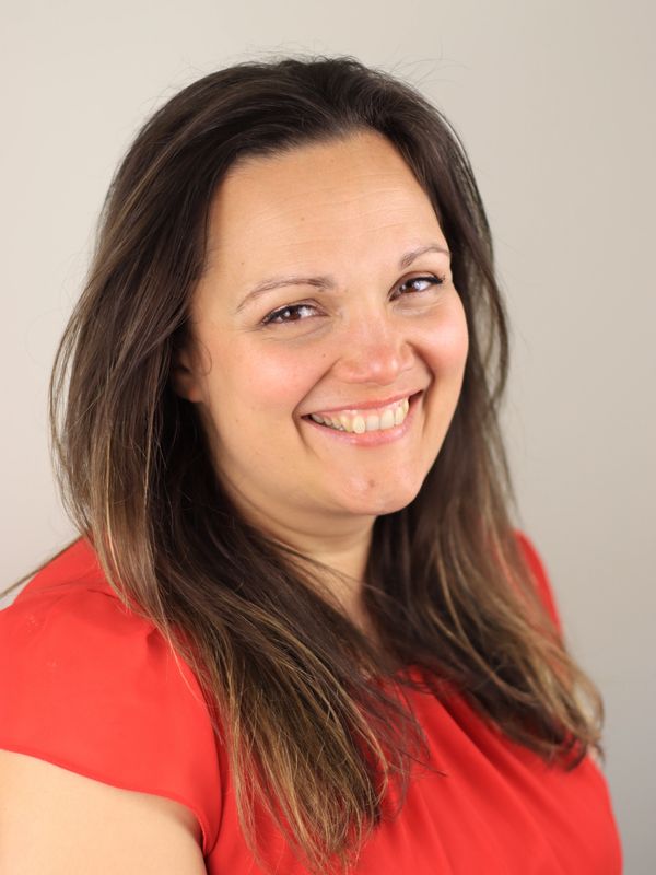 Smiling woman with long brown hair wearing a red top.