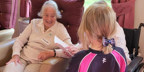 Elderly woman smiling at a young girl in a cozy room.