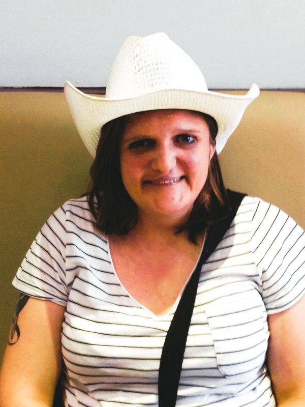 Woman wearing a white cowboy hat and striped shirt.