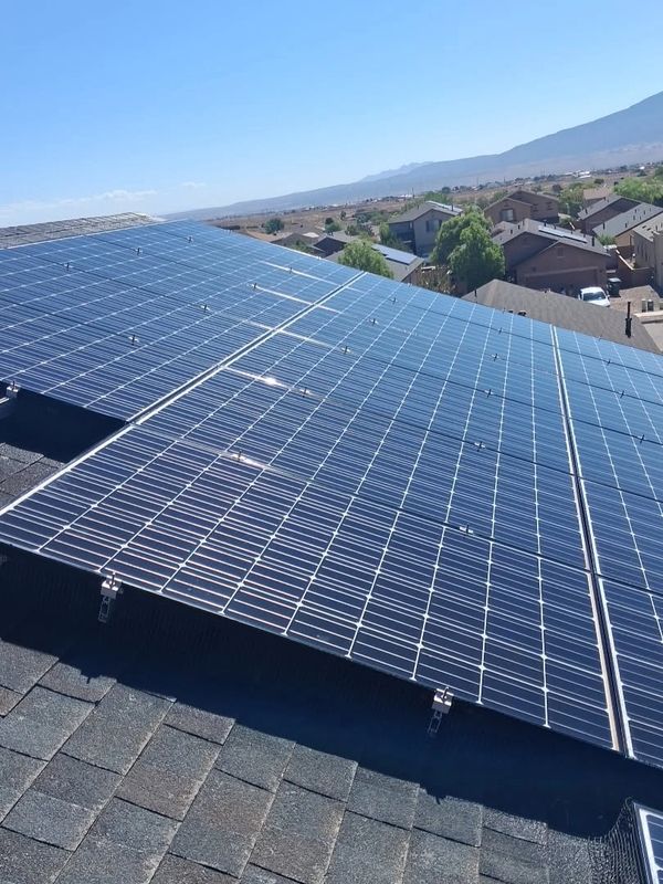 Solar panels installed on a residential roof under clear blue skies.