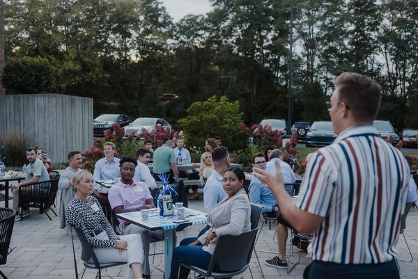 A man speaking to a group at an outdoor gathering in the evening.