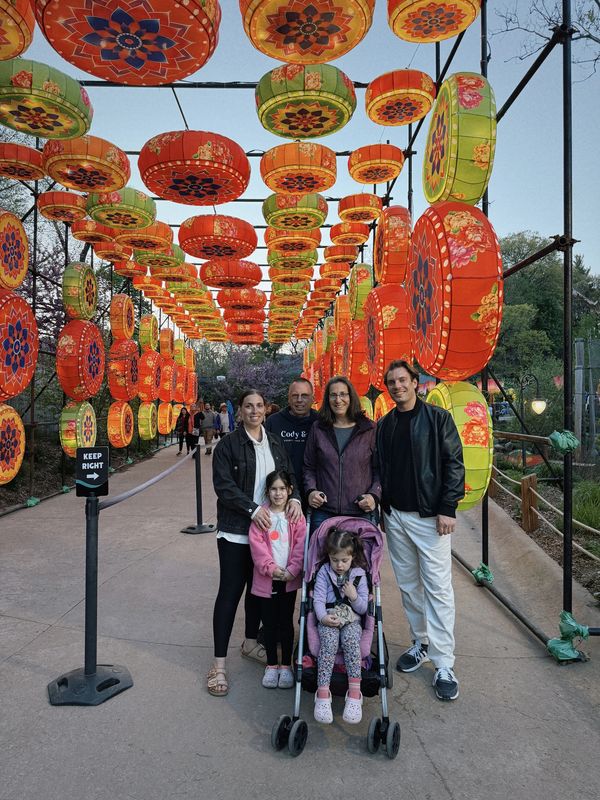 Family posing under colorful hanging lanterns at a festival.