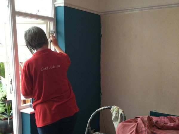 Woman in red t-shirt painting the window frame