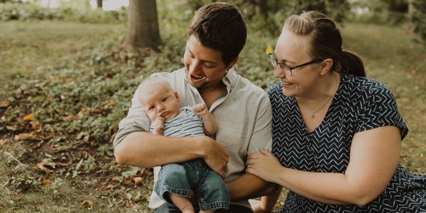 heterosexual couple holding baby in park