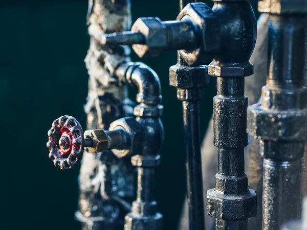Close-up of industrial metal pipes and a red valve.