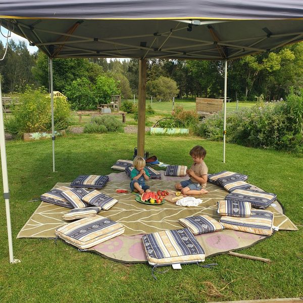 children eating fruit  in a circle of cushions at a community garden