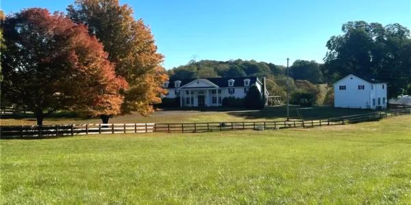 A large house with a spacious yard and autumn trees.