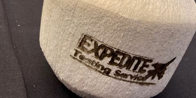 A white object with "EXPEDITE Testing Services" logo imprinted.