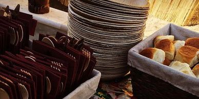 Stacks of plates, utensils, and bread rolls arranged for a meal.