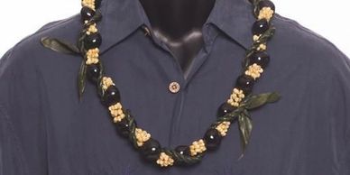 Black and beige floral necklace on a dark shirt.